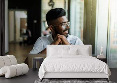 Young Asian Indian businessman using a notebook computer or laptop during office break at cafe, relaxing with a cup of coffee. Wall mural